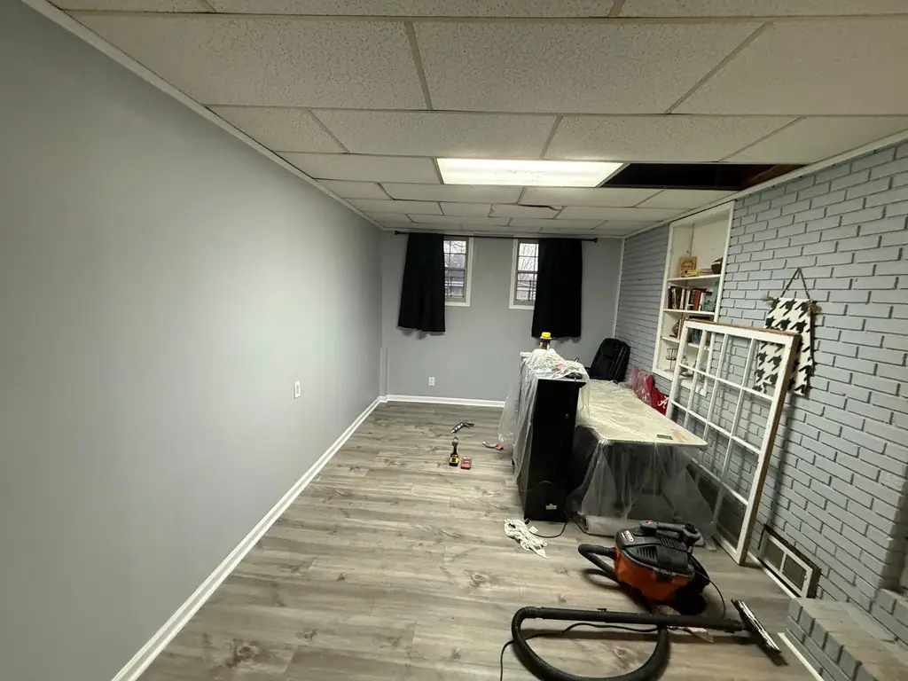 Finished basement room with grey walls and new plank flooring