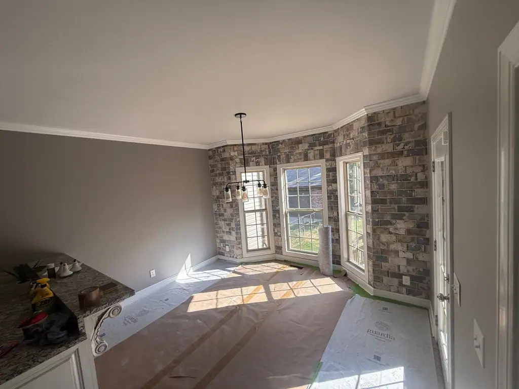 Room with a new brick accent wall and the floor covered for painting