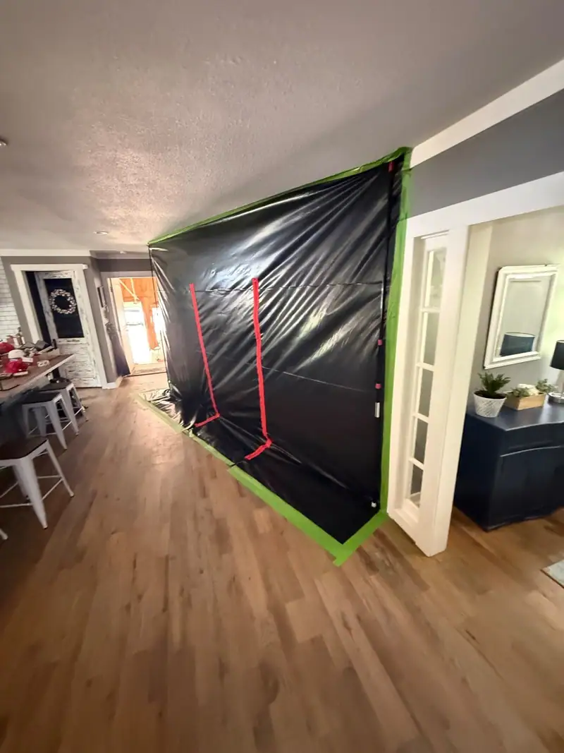 Black plastic containment wall sealed with green tape across a hallway