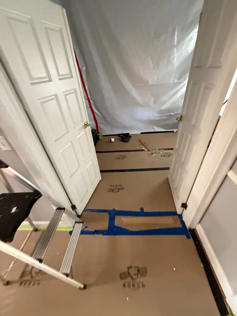 Doorway sealed in plastic with the floor covered in protection paper