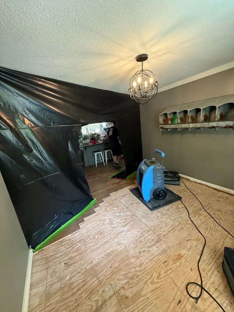 Containment wall and a dehumidifier in a dining room on bare subfloor
