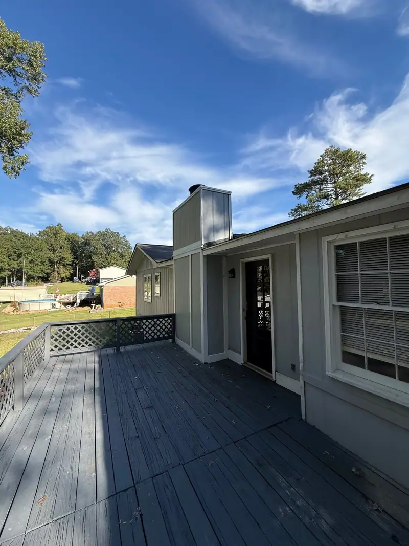Painted grey deck with lattice railing along the back of a house