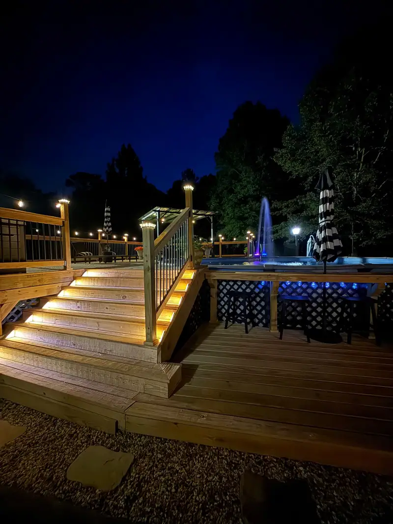 Lit deck stairs leading up to a pool deck at night