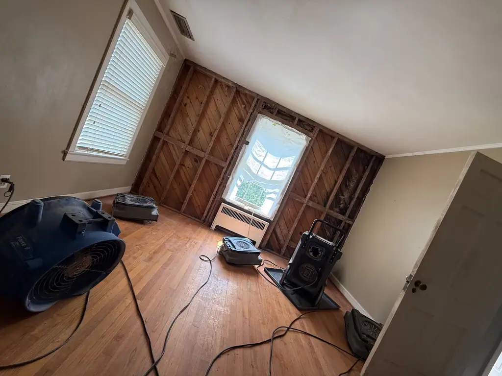 Hardwood floor drying with an air mover, wall opened to the studs under the window