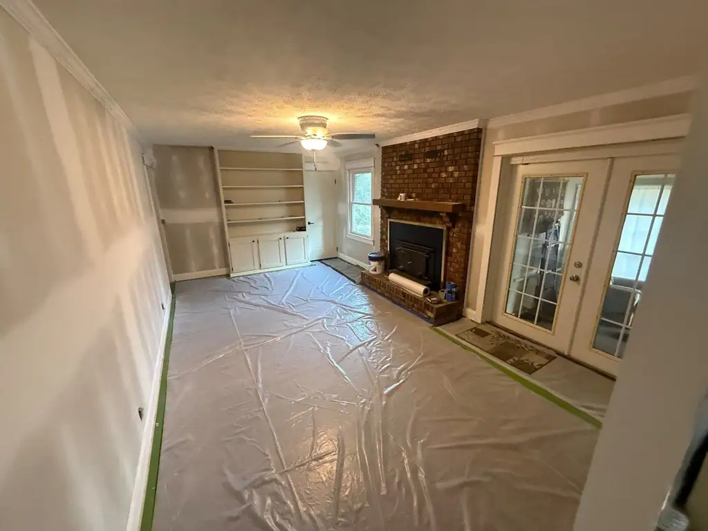 New drywall mudded around a brick fireplace, floor covered in plastic