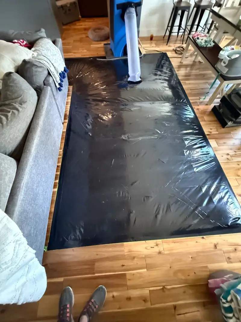 Floor-drying mats taped down over hardwood next to the sofa