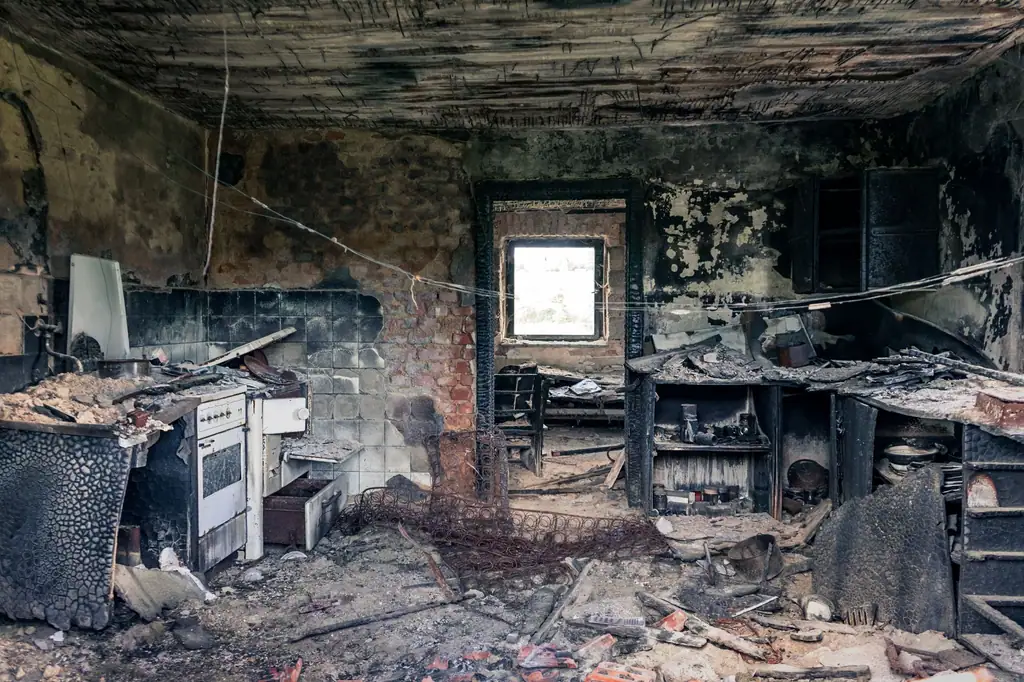 Kitchen after a fire, walls and cabinets black with soot
